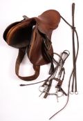 An English tan leather riding saddle, with nickel stirrups and snaffle,