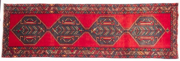 A Heriz runner, the red field with a row of four sea green hexagonal medallions,