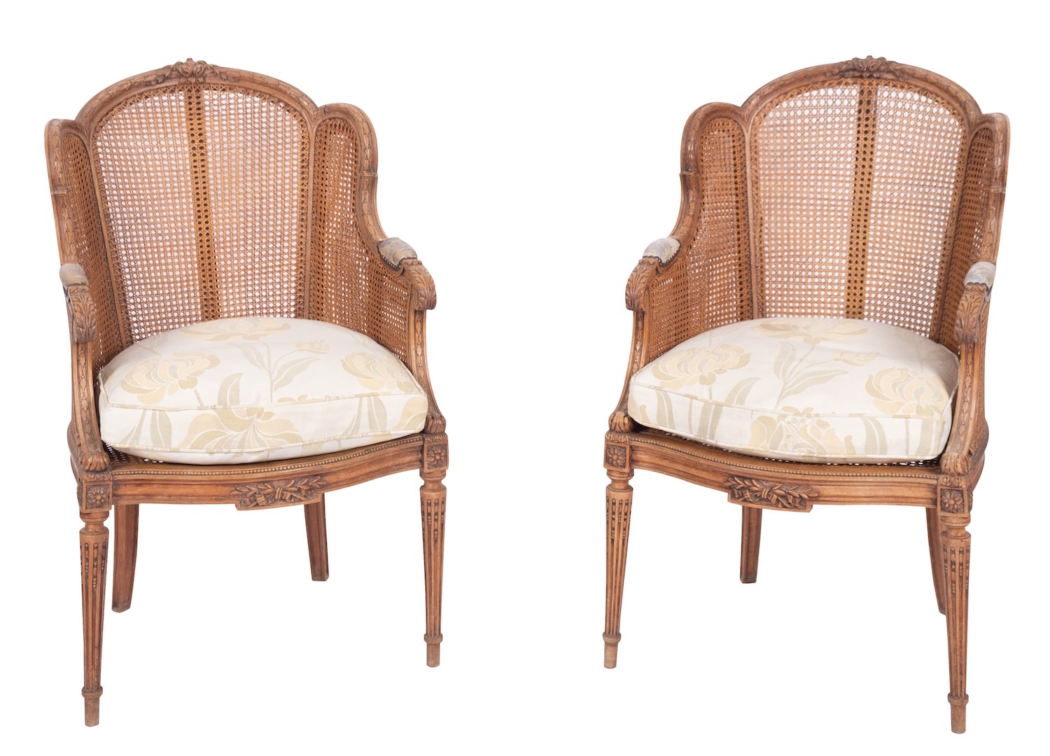 A pair of carved mahogany and caneworked bergere chairs, in Louis XVI style,