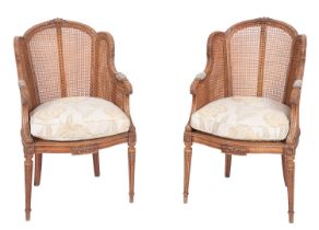 A pair of carved mahogany and caneworked bergere chairs, in Louis XVI style,