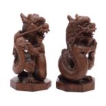 A pair of Chinese hardwood 'dragon' carvings with ebony eyes, on octagonal bases,