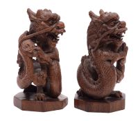A pair of Chinese hardwood 'dragon' carvings with ebony eyes, on octagonal bases,