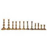 A large group of brass candlesticks, late 19th century; comprising a pair with fluted knops,