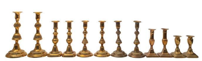 A large group of brass candlesticks, late 19th century; comprising a pair with fluted knops,