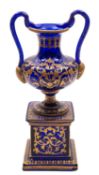 A blue glass and gilt decorated pedestal ewer with serpent handles, 28cm.