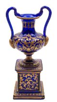 A blue glass and gilt decorated pedestal ewer with serpent handles, 28cm.