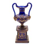 A blue glass and gilt decorated pedestal ewer with serpent handles, 28cm.