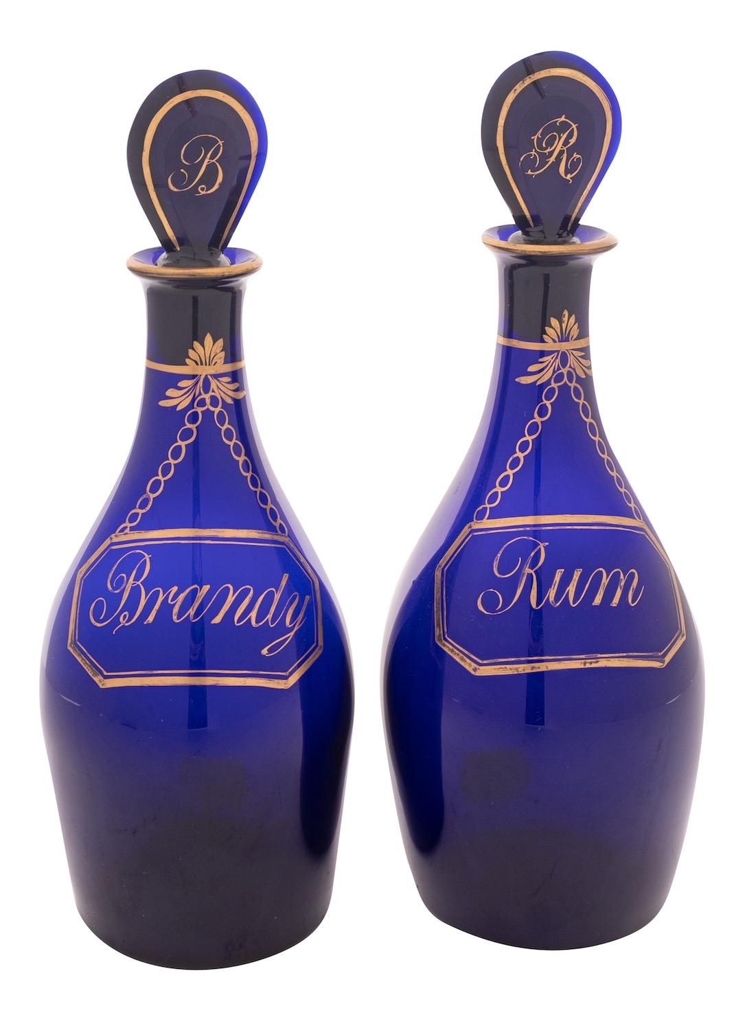A pair of Bristol blue glass 'Rum' and 'Brandy' decanters and stoppers the baluster bodies with