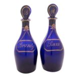 A pair of Bristol blue glass 'Rum' and 'Brandy' decanters and stoppers the baluster bodies with