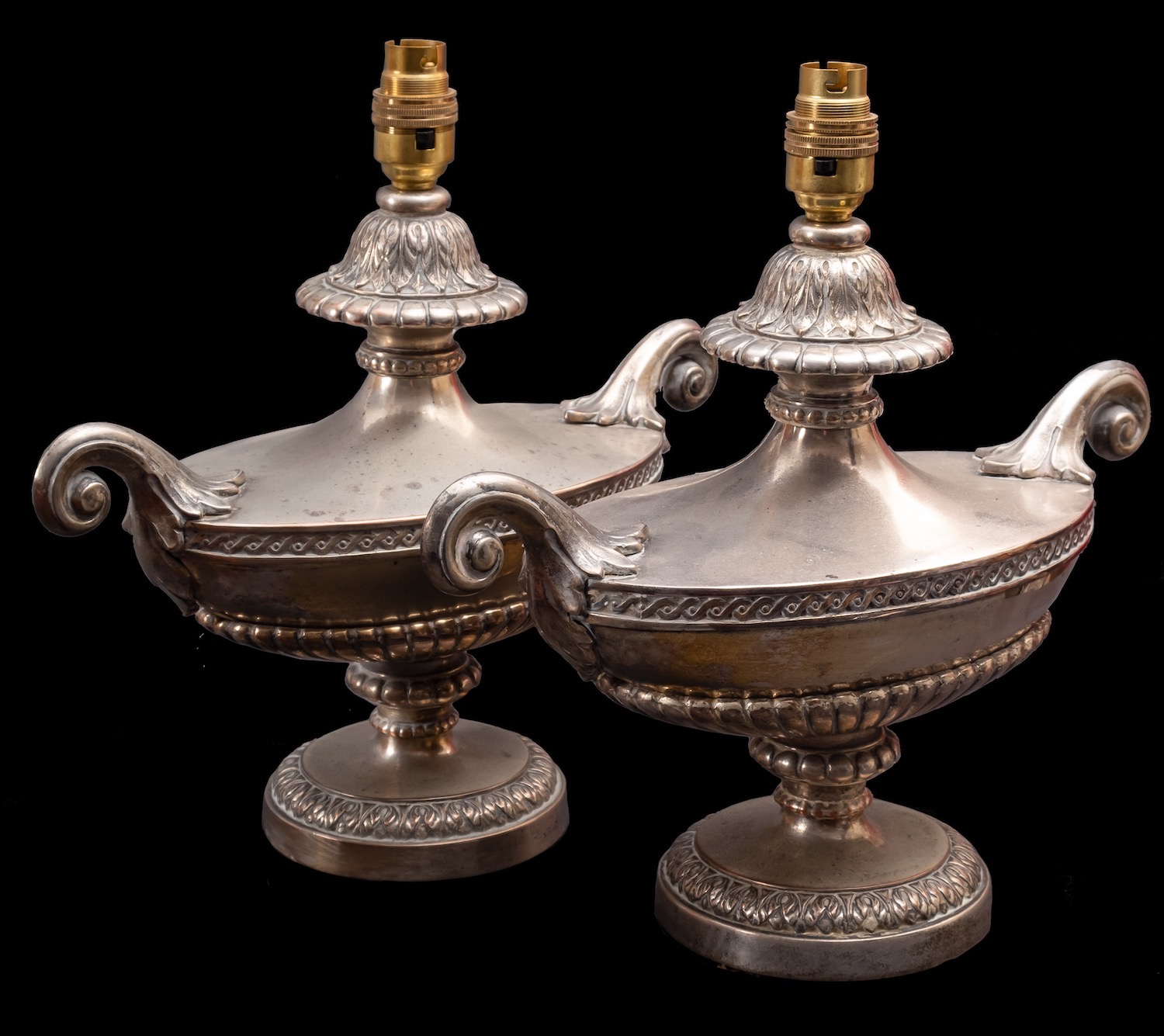 A pair of silver plated metal twin-handled urns fitted as table lamps,