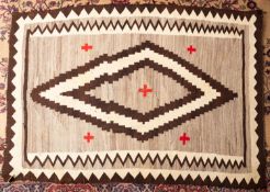 A Navajo flatweave, the beige field with a central chocolate brown and ivory lozenge medallion,