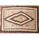 A Navajo flatweave, the beige field with a central chocolate brown and ivory lozenge medallion,