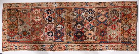 An Anatolian Kilim, the panelled field with a design of serrated lozenges in various colours,