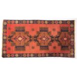 An Afghan rug, the brick red field with triple stepped and shaded geometric medallions,