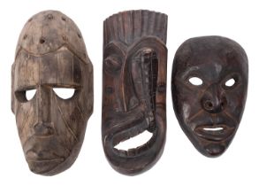Three carved wood tribal masks, 20th century; including one with a cobra rising from the open mouth,