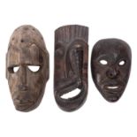 Three carved wood tribal masks, 20th century; including one with a cobra rising from the open mouth,