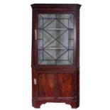 A George III mahogany and glazed corner display cabinet, early 19th century; with moulded cornice,