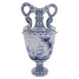 A large Dutch Delft pedestal vase with entwined serpent handles terminating in grotesque masks,