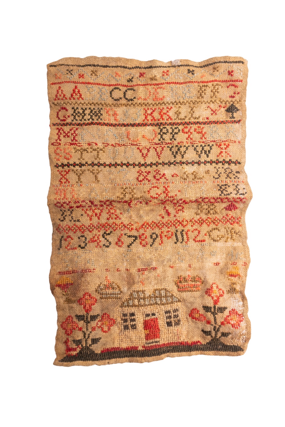 An early 19th century sampler, with alphabet in multi-colours, above a house flanked by flowers, - Image 4 of 4