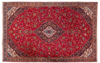 A Kashan carpet, the madder cartouche field with a central indigo shaped lozenge pole medallion,
