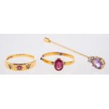 Two antique rings and a stick pin, including a three stone ring set with an oval-cut red stone,