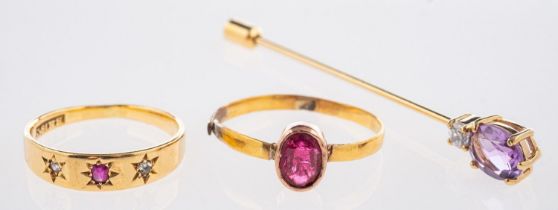 Two antique rings and a stick pin, including a three stone ring set with an oval-cut red stone,