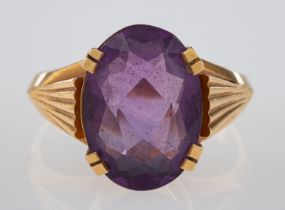 An amethyst dress ring set with an oval faceted amethyst, the shoulders cut with fan form grooves,