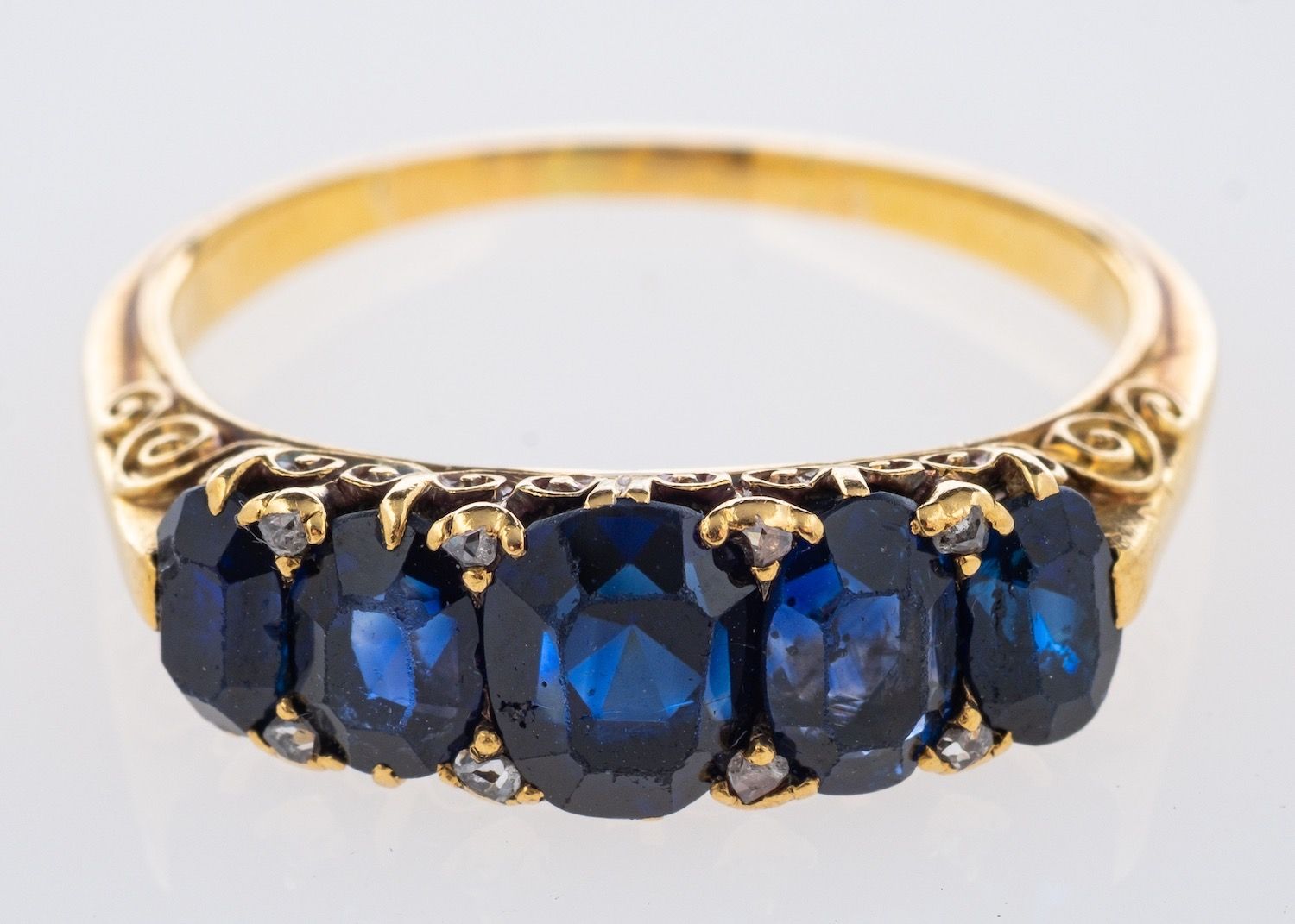 A five stone ring set, with oval-cut sapphires in a scroll designed setting, sapphires approx. 3.