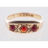 A 9ct yellow gold Edwardian ring, a 'gypsy' style setting with three circular-cut red stones,