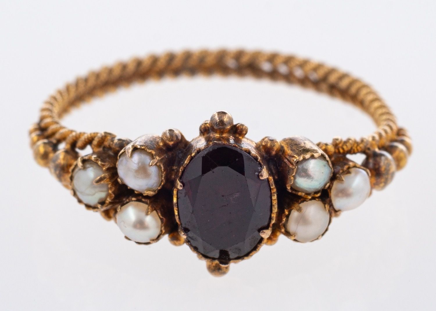 An antique closed back ring, set centrally with an oval-cut red stone (possibly garnet),