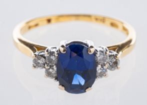 An 18ct yellow & white gold ring, set to the centre with an oval-cut synthetic sapphire,