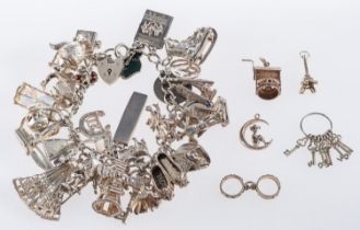 A silver heart padlock charm bracelet with numerous silver charms to include a concorde, boat,
