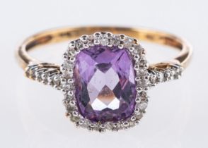 An amethyst and diamond ring, of cluster style and set with a rectangular mixed-cut amethyst,