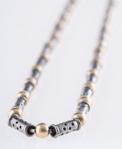 A bi-colour necklace, of pierced metal tubular beads interspaced by yellow metal rondel's,
