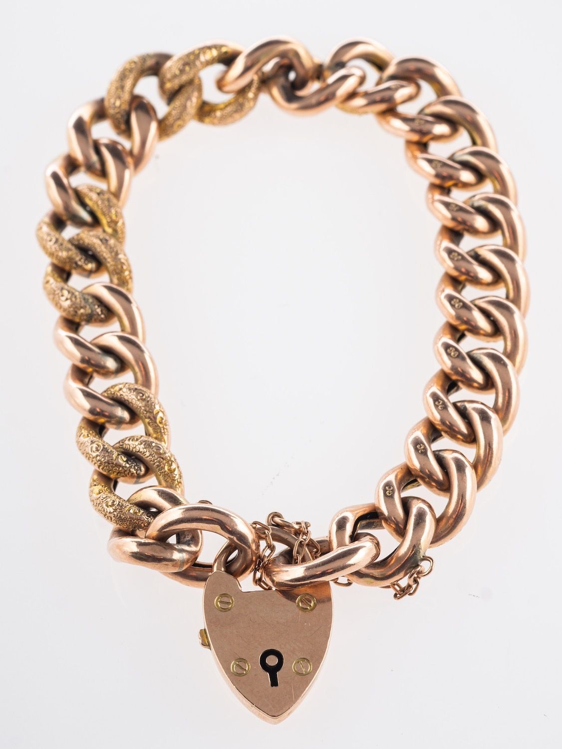 A heart padlock bracelet, with textured and polished curb links, safety chain, marked 9ct,