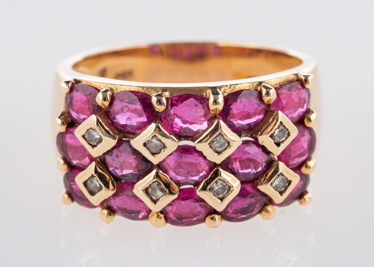A ruby & diamond ring, a wide band set with three rows of oval-cut rubies,