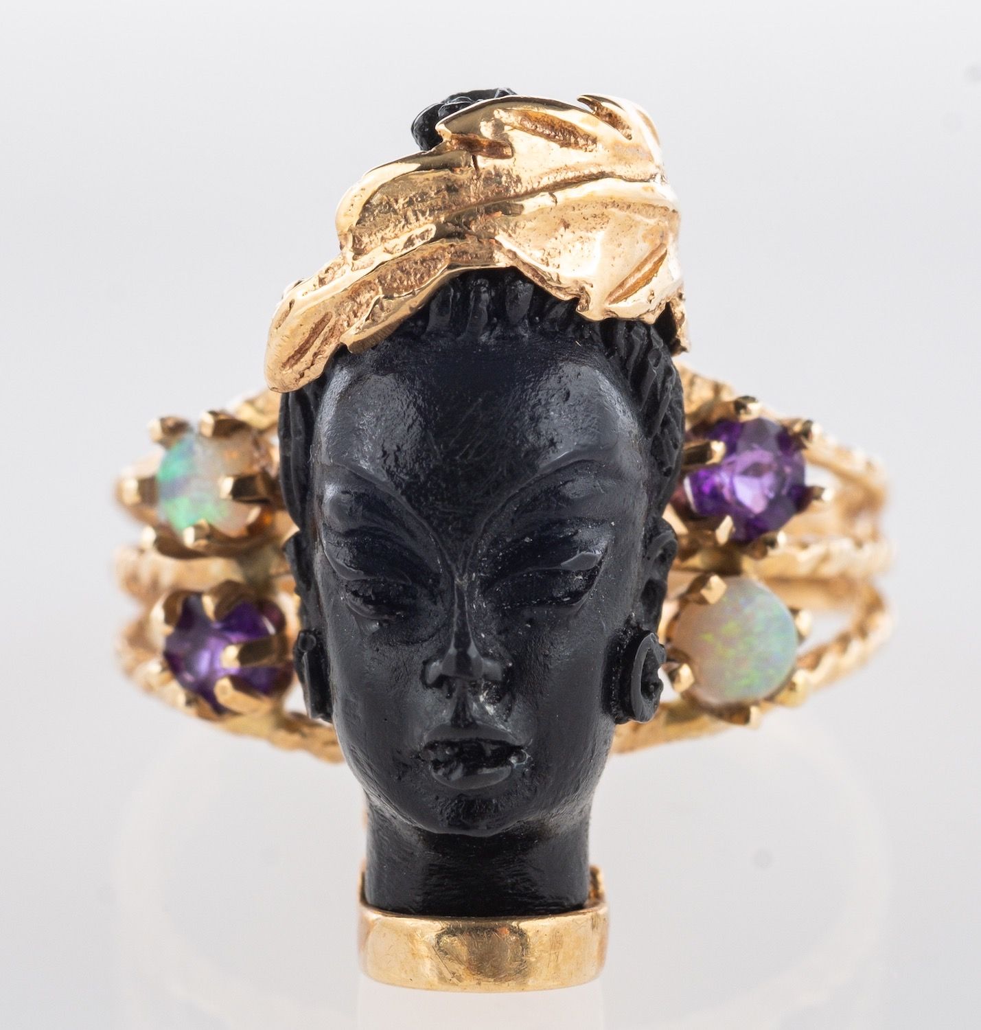 A Blackamoor ring, the carved head with foliate hair wreath,