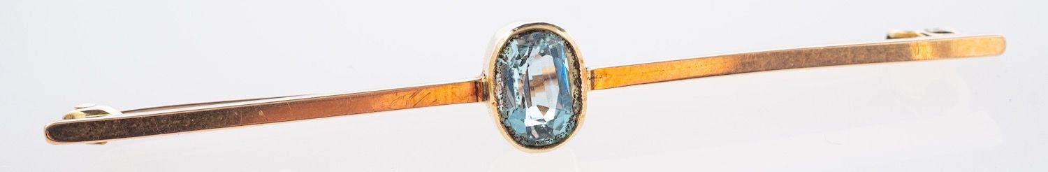 A bar brooch, collet & milgrain set with an oval-cut aquamarine, marked 15ct, length 5.50cm, 2.