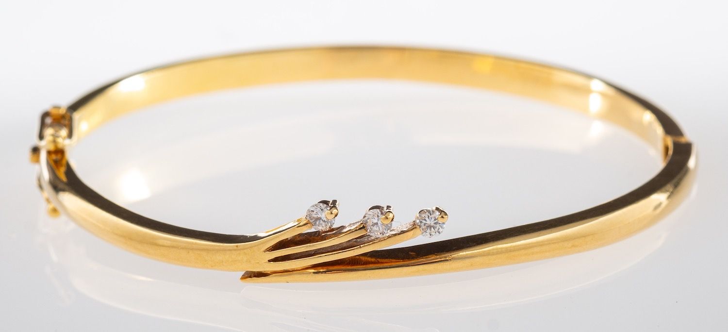 A diamond bangle, designed with a spray of three brilliant-cut diamonds, hinged, (hinge broken),