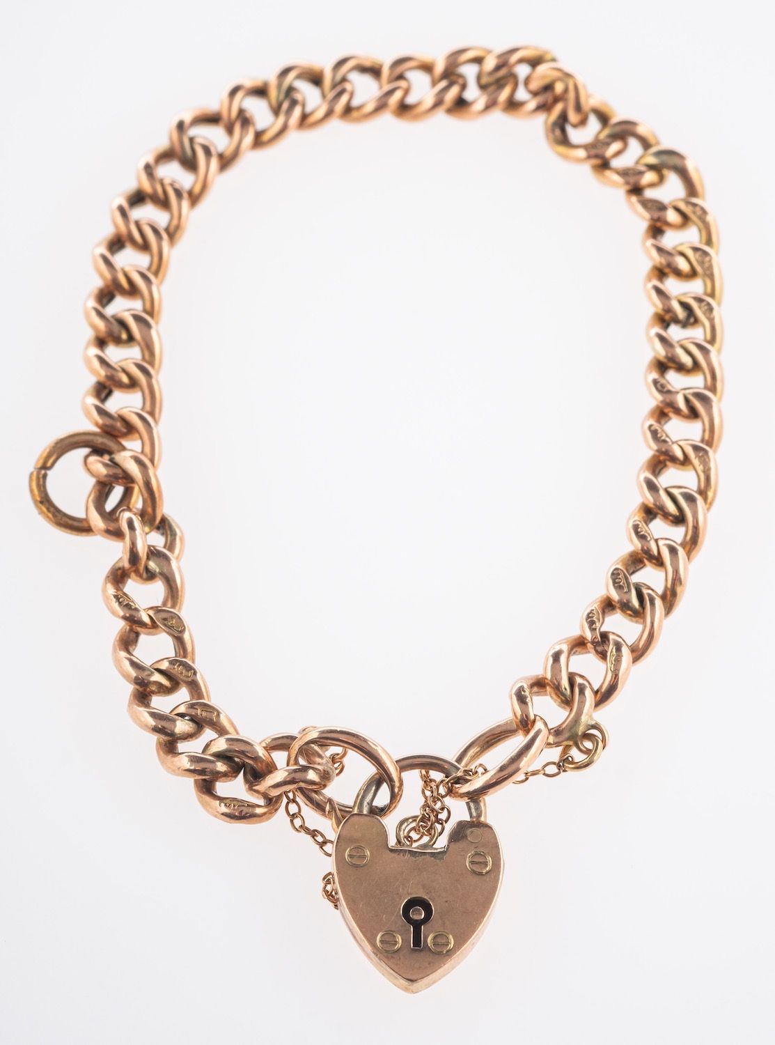 A curb bracelet, with heart padlock, safety chain and extra links, marked 9ct, length approx. 18.