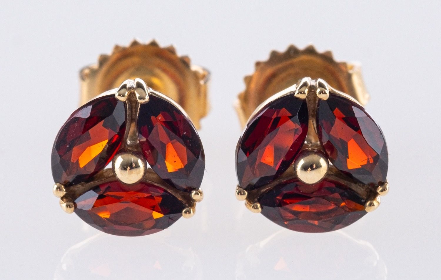 A pair of 9ct yellow gold & garnet stud earrings, each set with three marquise-cut garnets,