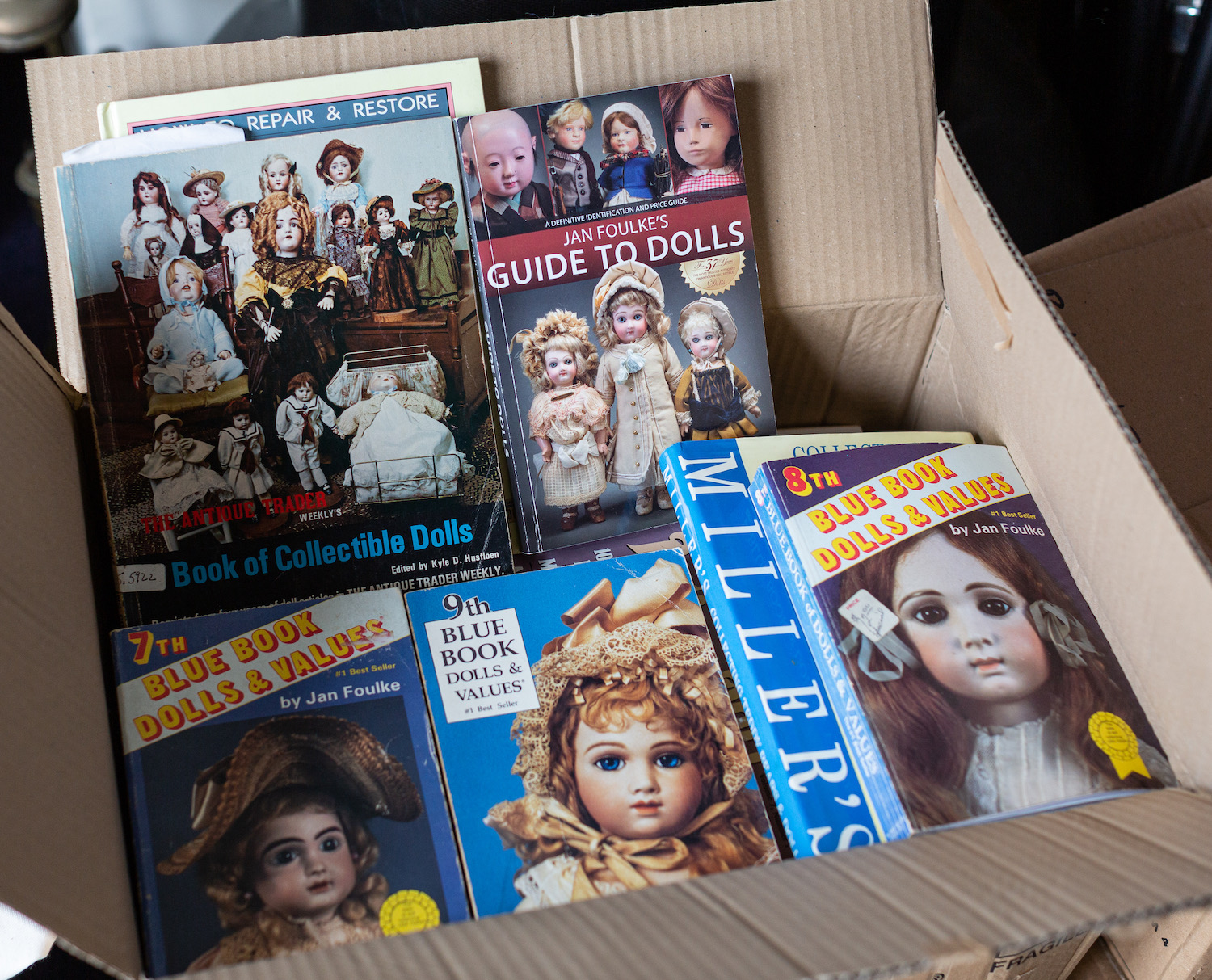 Four boxes of books and auction catalogues relating to dolls