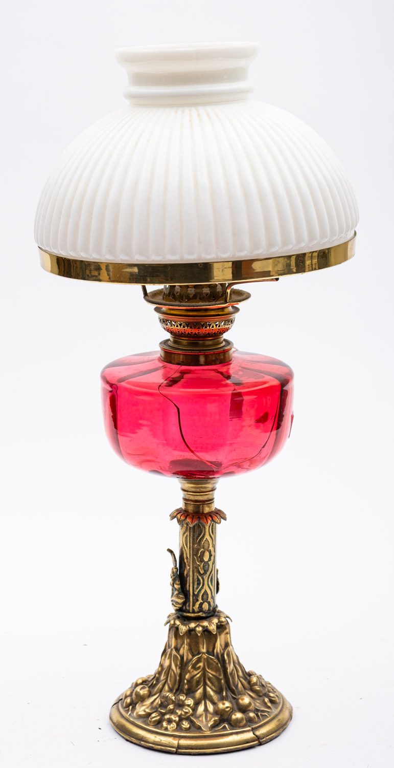 A late Victorian brass oil lamp with reeded opaque white glass shade and cranberry glass circular