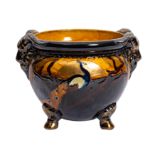 A Phoenix ware pottery jardiniere with moulded decoration of a peacock, in brown and ochre glazes.