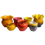 A collection of seven glazed pottery jardinieres in bright colours.