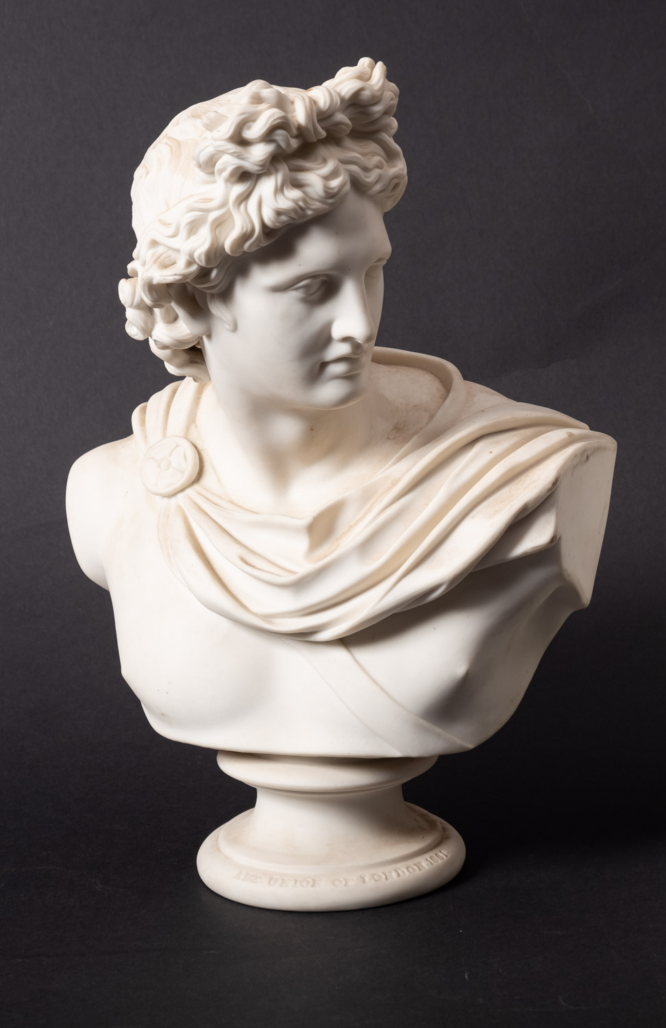 A Parian ware classical bust of Apollo, on circular socle, inscribed 'C DELPECH',