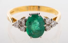 An 18ct gold emerald and diamond ring, claw set to the centre with an oval-cut emerald,