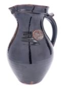 A large stoneware jug of bellied form with strap handle and thumb rest and pinched spout,