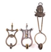 A brass finish skirt or hem lifter, with female mask surmount,