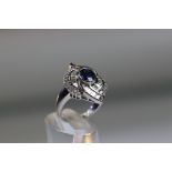 A contemporary Sapphire and Diamond Cluster Ring,the oval shaped central sapphire with rub over